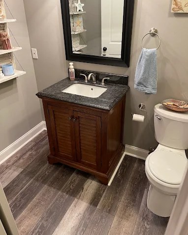 Remodeled bathroom with a wood vanity, stone top, and new plank flooring