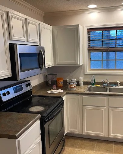 Kitchen with cabinets refinished in clean white over a stainless range